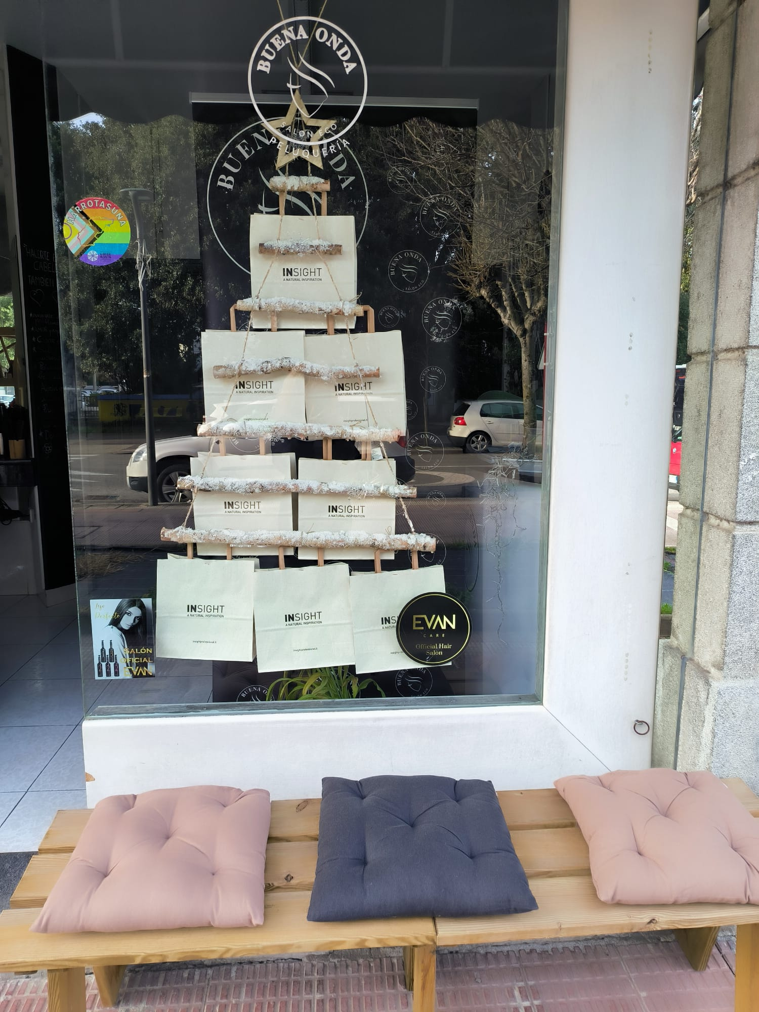 Escaparate de la peluquería Buena Onda antes de la edición, con pegatinas en el cristal y reflejos del entorno